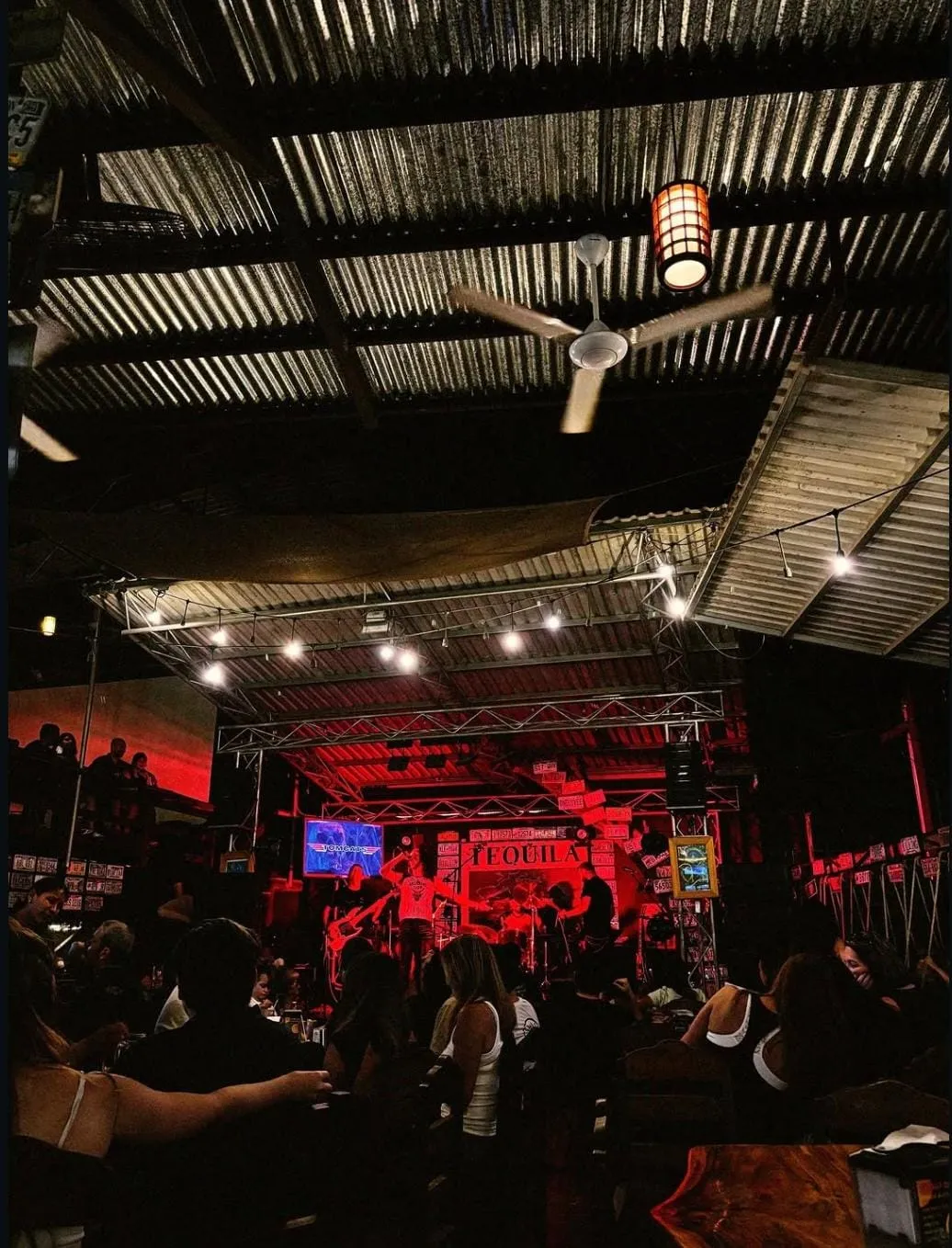 Músicos tocando bajo luces rojas en el Tequila Stage de Coconutz